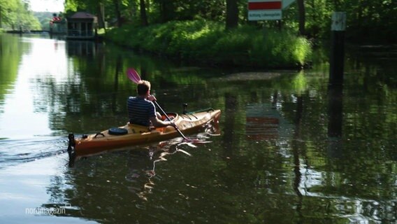 Ein Mann paddelt auf einem kleinen Fluss. © Screenshot 