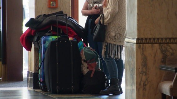 Zwei Frauen stehen mit ihren Koffern in einer Hotellobby. © Screenshot 