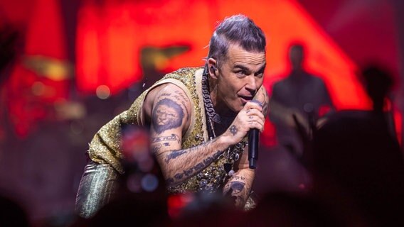 Robbie Williams lehnt sich singend nach vorne beim Konzert in Hamburg am 1. Februar 2023 © NDR 2 Foto: Axel Herzig