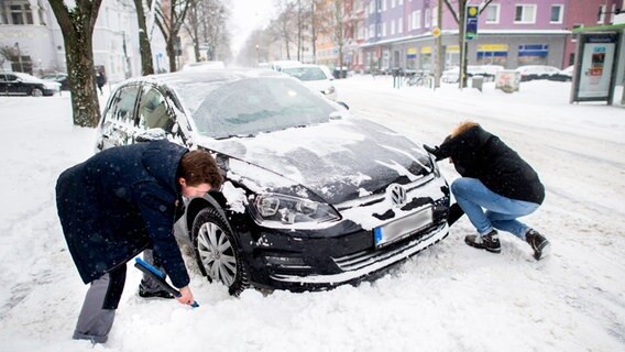 Zwei Personen entfernen Schnee vor den Rädern eines festgefahrenen Auto. © dpa Bildfunk Foto: Hauke-Christian Dittrich