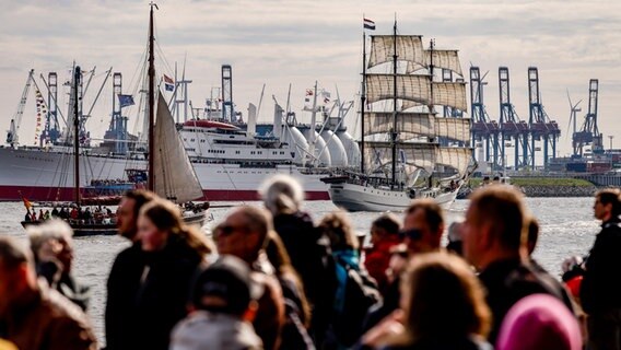 Besucher des Hamburger Hafengeburtstags beobachten Schiffe auf der Elbe. © picture alliance/dpa Foto: Axel Heimken